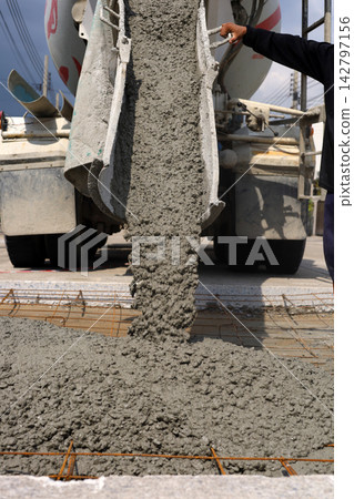 Wet cement pouring from a mixer truck chute onto a steel wire mesh for road Wet cement pouring from a mixer truck chute onto a steel wire mesh for road 142797156