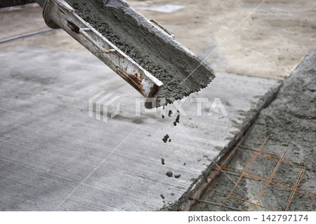 Wet cement pouring from a mixer truck chute onto a steel wire mesh for road Wet cement pouring from a mixer truck chute onto a steel wire mesh for road 142797174