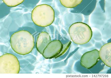 Fresh cucumber slices floating in clear, rippling water Fresh cucumber slices floating in clear, rippling water 142797208