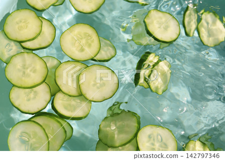 Fresh cucumber slices floating in clear, rippling water Fresh cucumber slices floating in clear, rippling water 142797346