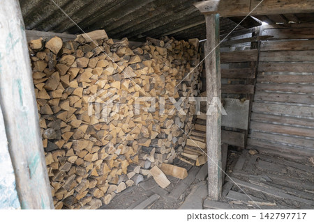 Neatly stacked dry firewood logs neatly arranged inside a rustic wooden shed for winter heating, natural chopped timber storage structure in a rural country barn. Neatly stacked dry firewood logs neatly arranged inside a rustic wooden shed for winter heating, natural chopped timber storage structure in a rural country barn. 142797717