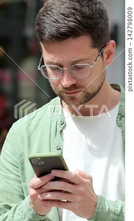 Vertical video. Man on city street using smartphone for messaging and browsing. Vertical video. Man on city street using smartphone for messaging and browsing. 142798009