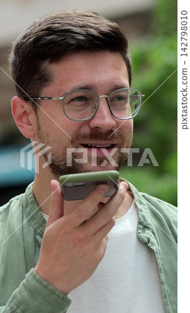 Vertical video. Recording Voice Message on Mobile Phone: Young Man in Glasses. Vertical video. Recording Voice Message on Mobile Phone: Young Man in Glasses. 142798010