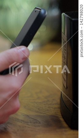 Vertical video. Unrecognizable man scanning QR code on table in restaurant or cafe. Online menu for clients. Convenience, contactless concept. Vertical video. Unrecognizable man scanning QR code on table in restaurant or cafe. Online menu for clients. Convenience, contactless concept. 142798020