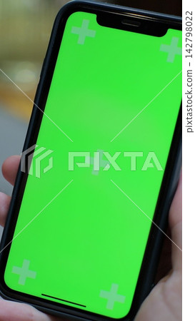 Vertical video. Close up of man hands using green screen smartphone in the cafe. Mock-up for tracking. Watching content video blog and surfing internet. Vertical video. Close up of man hands using green screen smartphone in the cafe. Mock-up for tracking. Watching content video blog and surfing internet. 142798022
