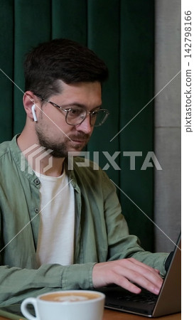 Vertical video. Person using laptop at cafe table for remote work. Vertical video. Person using laptop at cafe table for remote work. 142798166