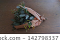 An overhead photograph of a fresh eucalyptus bouquet wrapped in English newspaper, placed on a wooden table. An overhead photograph of a fresh eucalyptus bouquet wrapped in English newspaper, placed on a wooden table. 142798337