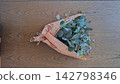 An overhead photograph of a fresh eucalyptus bouquet wrapped in English newspaper, placed on a wooden table. An overhead photograph of a fresh eucalyptus bouquet wrapped in English newspaper, placed on a wooden table. 142798346