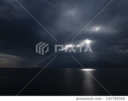 Dramatic light beams between clouds above ocean Dramatic light beams between clouds above ocean 142798366