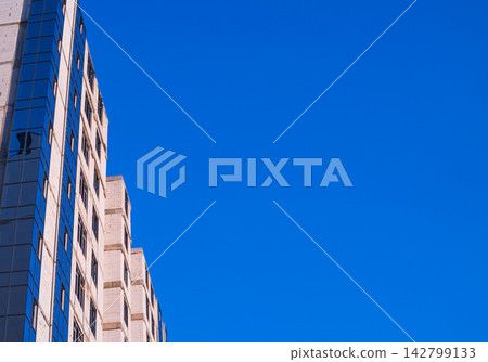 Walls of multi-storey building during construction and installation of new plastic windows is isolated on clear blue sky background. Frame and masonry are not yet hidden by decorative cladding Walls of multi-storey building during construction and installation of new plastic windows is isolated on clear blue sky background. Frame and masonry are not yet hidden by decorative cladding 142799133
