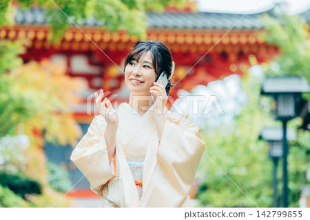 A woman in a kimono praying at a shrine 142799855