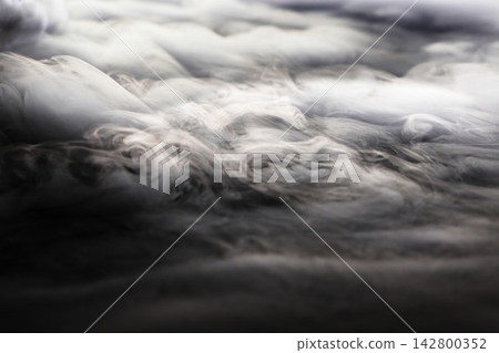 Dry ice smoke and fog spread across a black background. 142800352