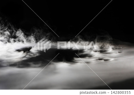 Dry ice smoke and fog spread across a black background. 142800355