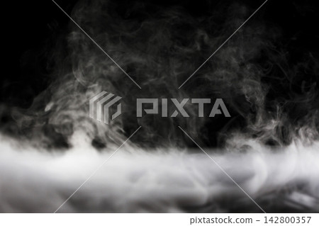 乾冰產生的煙霧和薄霧在黑色背景上蔓延開來。 乾冰產生的煙霧和薄霧在黑色背景上蔓延開來。 142800357