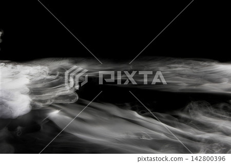 Dry ice smoke and fog spread across a black background. 142800396