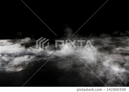 乾冰產生的煙霧和薄霧在黑色背景上蔓延開來。 乾冰產生的煙霧和薄霧在黑色背景上蔓延開來。 142800398