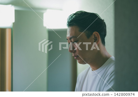 一位中年男子低頭,憂心忡忡地進行著他的保養步驟。 一位中年男子低頭,憂心忡忡地進行著他的保養步驟。 142800974