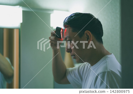 40多歲男士的美容程序:使用頭皮刷進行頭皮護理。 40多歲男士的美容程序:使用頭皮刷進行頭皮護理。 142800975