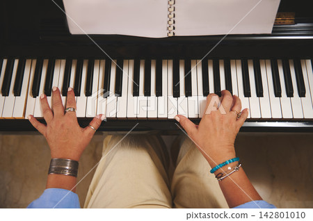 Woman playing piano with sheet-music, close-up of hands on keys and rings Woman playing piano with sheet-music, close-up of hands on keys and rings 142801010