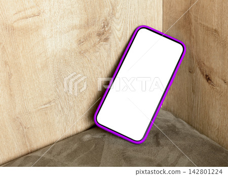 Smartphone with a blank display and a pink-purple frame leans against a wooden corner. The mobile Smartphone with a blank display and a pink-purple frame leans against a wooden corner. The mobile 142801224