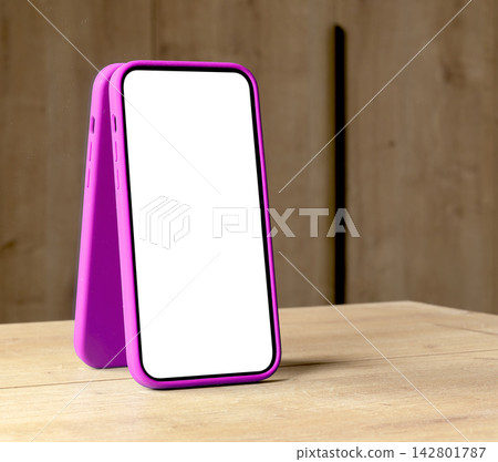 Pair of smartphone mockups with blank white screens and magenta frames lean together on a wooden Pair of smartphone mockups with blank white screens and magenta frames lean together on a wooden 142801787