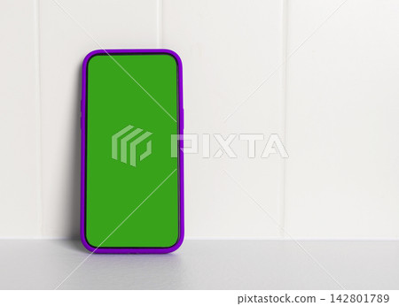 Phone mockup with a bright green chroma key screen and purple frame stands vertically on a plain Phone mockup with a bright green chroma key screen and purple frame stands vertically on a plain 142801789