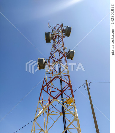 Looking up at a towering red and white telecommunication mast against a bright blue sky, evoking a strong sense of global connectivity, technological progress, and hope. Nobody. Looking up at a towering red and white telecommunication mast against a bright blue sky, evoking a strong sense of global connectivity, technological progress, and hope. Nobody. 142801958