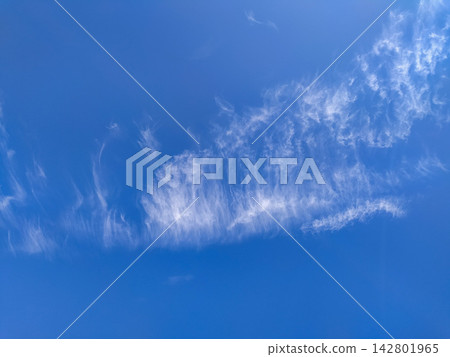 Wispy white cirrus clouds drift across a vibrant blue sky, evoking a sense of peaceful freedom and tranquility. A serene background with no people, perfect for wellness and nature concepts. Wispy white cirrus clouds drift across a vibrant blue sky, evoking a sense of peaceful freedom and tranquility. A serene background with no people, perfect for wellness and nature concepts. 142801965