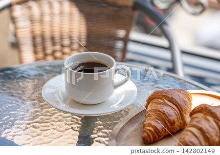 Coffee and Fresh Croissants on a Sunny Outdoor Cafe Table Coffee and Fresh Croissants on a Sunny Outdoor Cafe Table 142802149