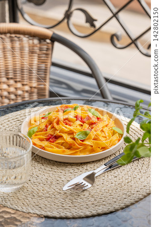 Homemade Tagliatelle with Tomato Sauce and Fresh Basil on Outdoor Cafe Table Homemade Tagliatelle with Tomato Sauce and Fresh Basil on Outdoor Cafe Table 142802150