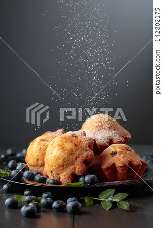 Freshly baked blueberry muffins are dusted with icing sugar. Freshly baked blueberry muffins are dusted with icing sugar. 142802175
