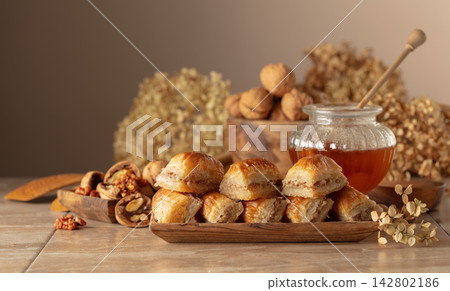 Baklava with walnuts and honey on a beige background. Baklava with walnuts and honey on a beige background. 142802186