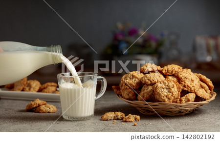 Oatmeal cookies and milk on a kitchen table. 142802192