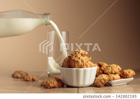 Oatmeal cookies and milk sit on a kitchen table. Oatmeal cookies and milk sit on a kitchen table. 142802193