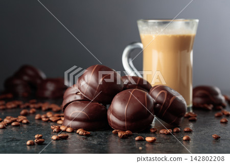 Chocolate dessert and cup of coffee with cream on a black table. Chocolate dessert and cup of coffee with cream on a black table. 142802208