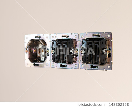 Electrical socket box mechanism mounted in white plaster wall. Triple metal power outlet Electrical socket box mechanism mounted in white plaster wall. Triple metal power outlet 142802338