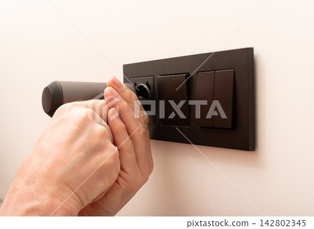 Electrician installing power socket box on wall with screwdriver tool. Repairman fixing black Electrician installing power socket box on wall with screwdriver tool. Repairman fixing black 142802345