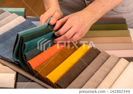 Fabric sample book with colorful upholstery tissue swatches. Hands turning pages of catalog on Fabric sample book with colorful upholstery tissue swatches. Hands turning pages of catalog on 142802349