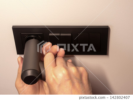 Power socket outlet installation using electric screwdriver tool. Electrician screwing black socket Power socket outlet installation using electric screwdriver tool. Electrician screwing black socket 142802407