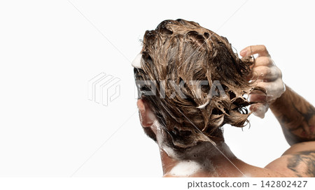 Man rubbing foamy shampoo through long wet hair from rear view 142802427