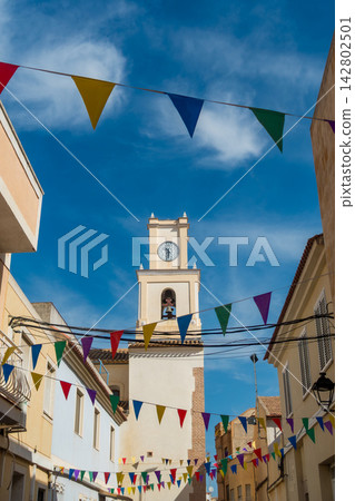 Church Clock Tower with Medieval Festive Bunting against a blue sky Church Clock Tower with Medieval Festive Bunting against a blue sky 142802501