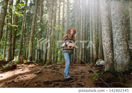 Woman with backpack hiking outdoors in the Forest. Trekking in the Pine Woods. Hiking lifestyle Woman with backpack hiking outdoors in the Forest. Trekking in the Pine Woods. Hiking lifestyle 142802545