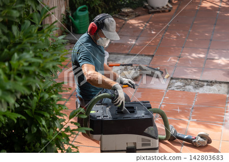 Worker cleaning outdoor terracotta tiles with vacuum and power tools Worker cleaning outdoor terracotta tiles with vacuum and power tools 142803683