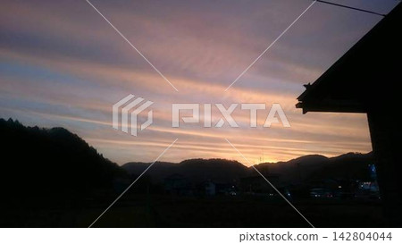 A sunset scene woven from layers of clouds and the silhouette of mountains. A sunset scene woven from layers of clouds and the silhouette of mountains. 142804044