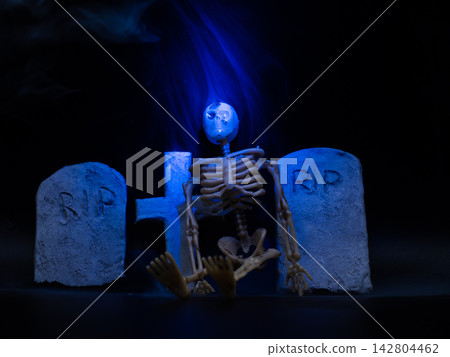 Skeleton in Halloween cemetery blue smoke black background Skeleton in Halloween cemetery blue smoke black background 142804462