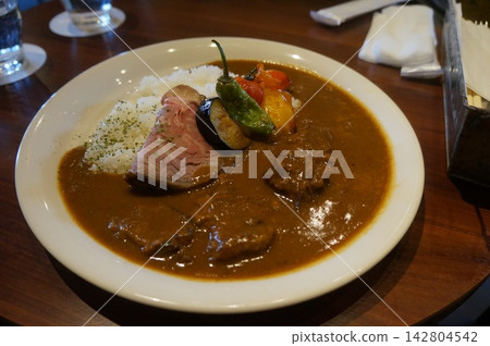 A photo of curry topped with vegetables A photo of curry topped with vegetables 142804542