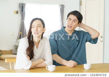一名年輕的日本男子雙手抱頭,懊悔不已;一名年輕的日本女子則一臉難以置信地別過臉去。 一名年輕的日本男子雙手抱頭,懊悔不已;一名年輕的日本女子則一臉難以置信地別過臉去。 142804728