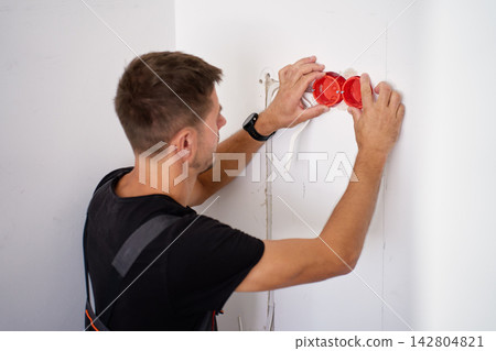 Man installing boxes for new electrical outlets Man installing boxes for new electrical outlets 142804821