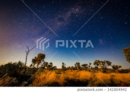 View of a star filled night sky above the rugged landscape of Karijini National Park in the Pilbara region of Western Australia, showing the remote natural environment beneath a clear dark sky. 142804942