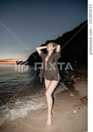 Atmospheric evening portrait of a curly haired woman posing on a sandy beach by the sea Atmospheric evening portrait of a curly haired woman posing on a sandy beach by the sea 142805013